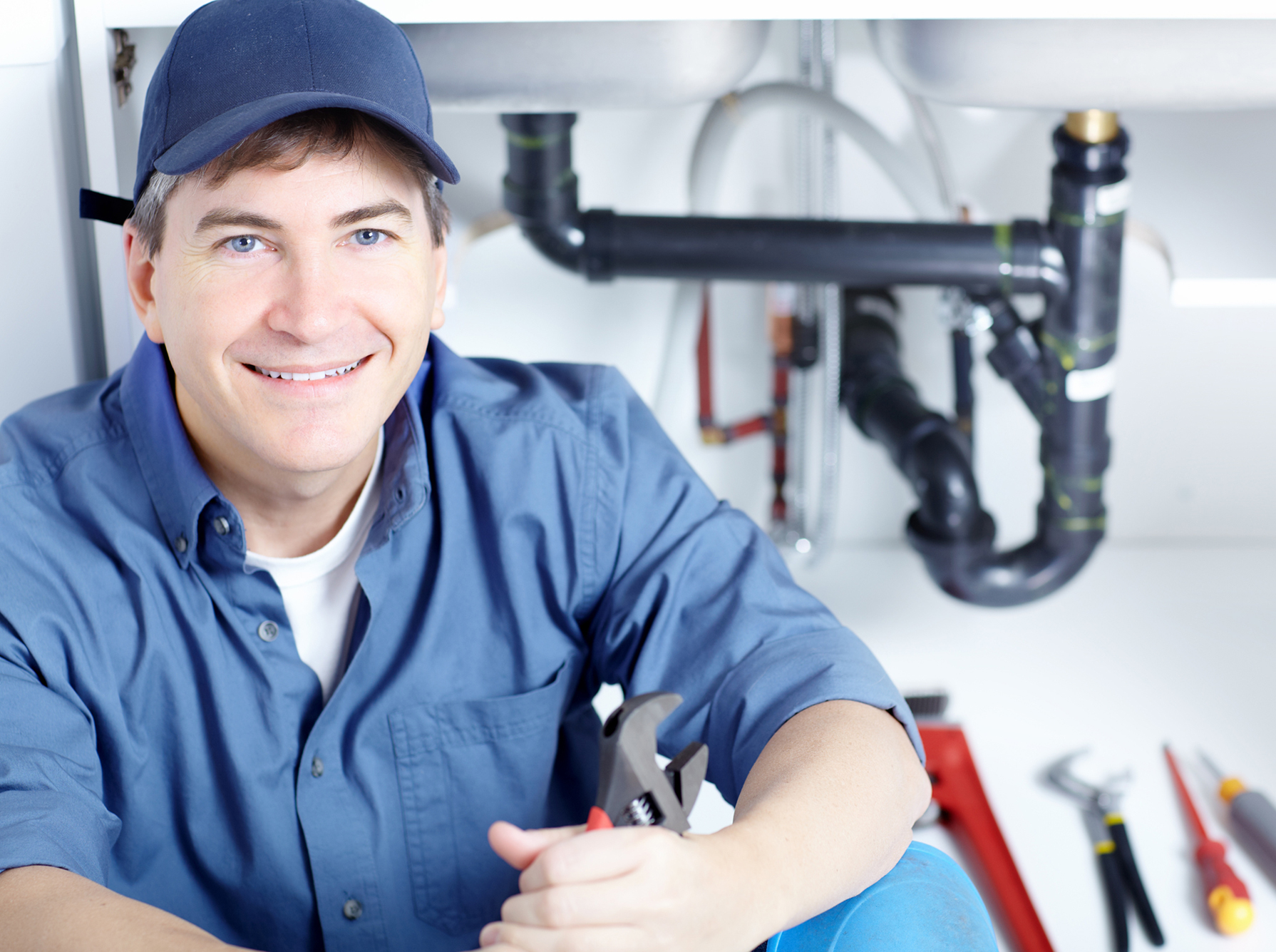 Plumber Fixing A Sink At Kitchen